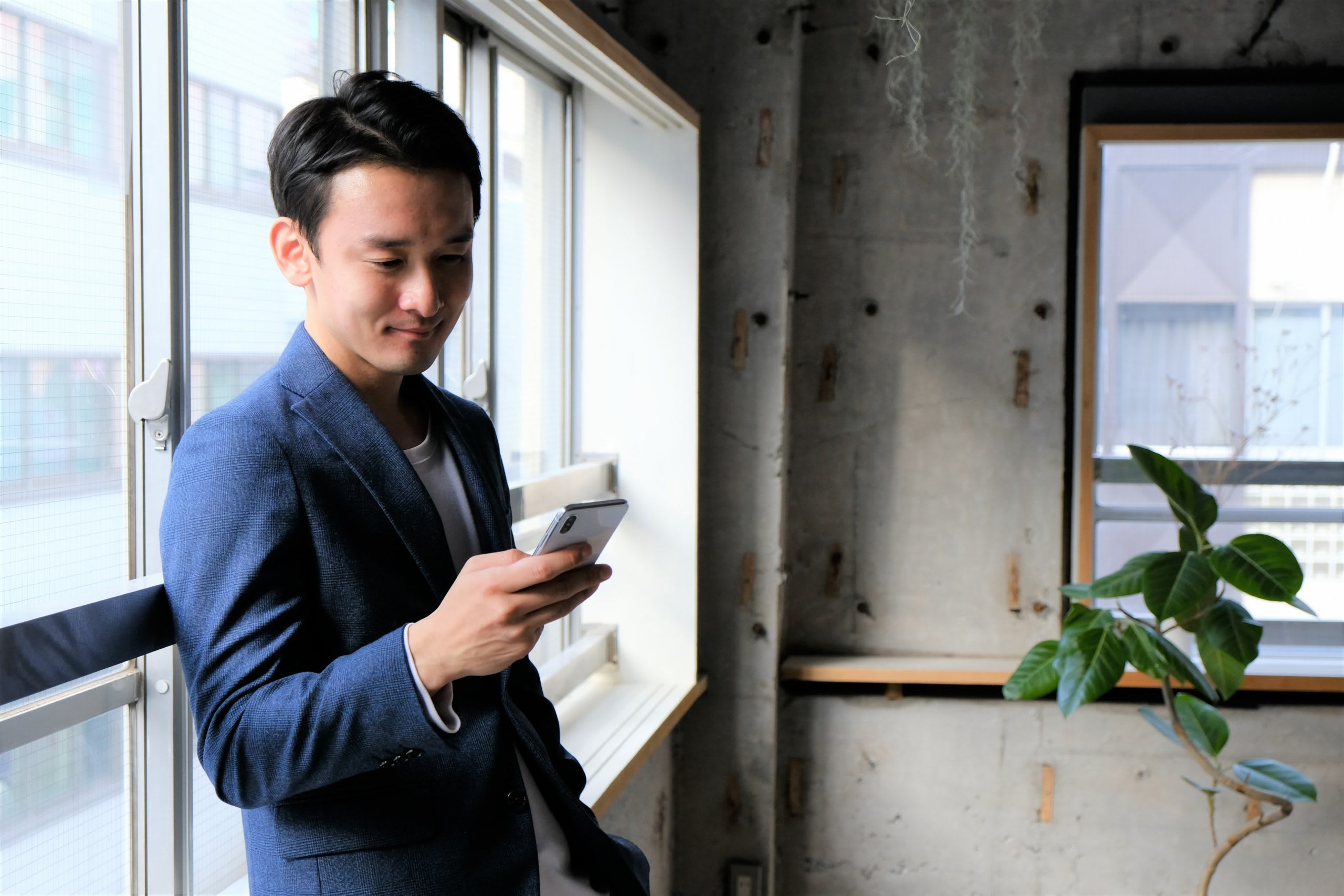 Person leans against window holding a cell phone.